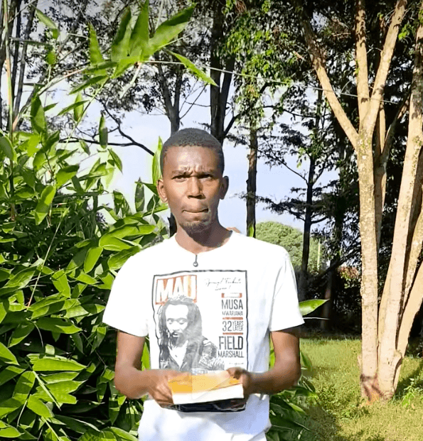Mugo wa Njoroge outdoors in Central Kenya, holding a book